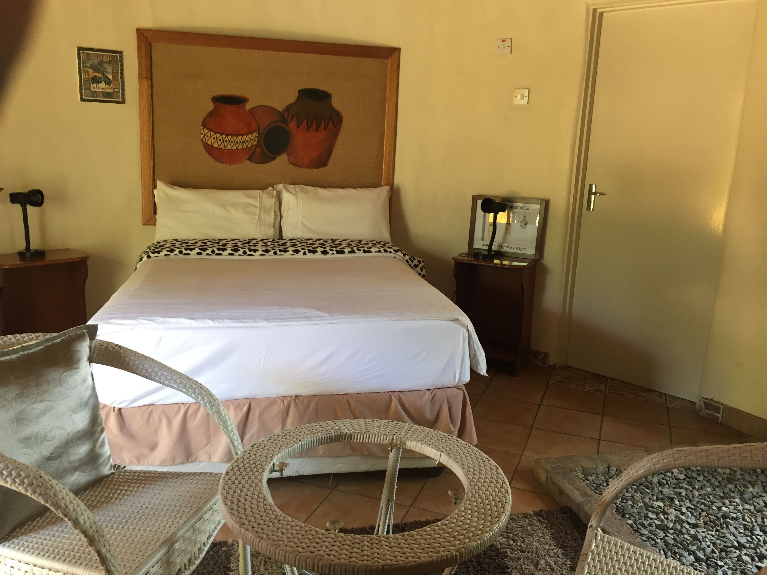A bedroom with a large bed, two nightstands, a mirror, and a chair.
