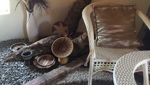Una silla de mimbre con respaldo acolchado, una cesta tejida y un jarrón decorativo con ramas.