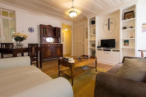 Una sala de estar con una mesa de centro de madera, un televisor y una estantería.