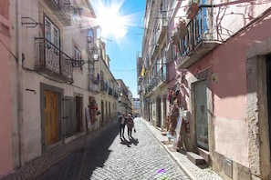 Una calle adoquinada estrecha flanqueada por edificios, algunos con balcones y macetas con flores.