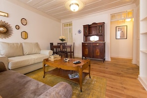 Una sala de estar con un sofá, una mesa de centro, un aparador de madera y un comedor con una mesa y sillas.
