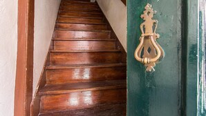 A wooden staircase leading to a door with a brass knocker.