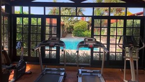 A gym with two treadmills and a pool visible through large windows. - Hotel Pousada Ourinhos (Ourinhos)