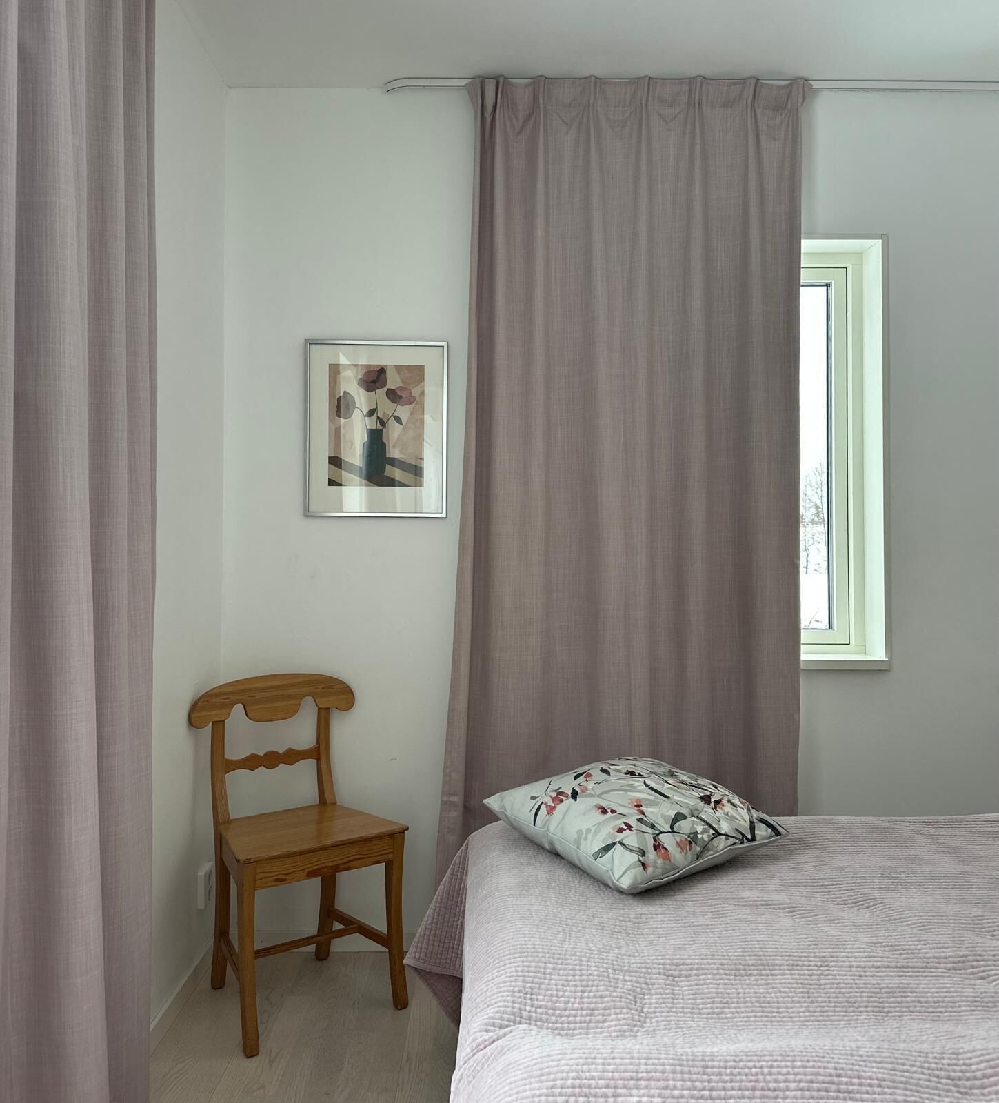 A bedroom with a bed, a chair, a window, and a picture on the wall.