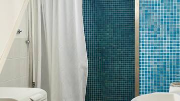 Un baño con ducha, inodoro blanco y paredes con azulejos azules.