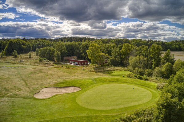 A golf course with bunkers and a clubhouse.