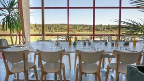 A dining area with tables set for a meal, large windows with a view of a forested landscape, and wooden chairs. - Kiladalens golf & Lodge (Nykoping)