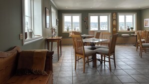 A spacious dining area with wooden chairs and a table, large windows with a view, and a cozy seating area with a bench. - Kiladalens golf & Lodge (Nykoping)