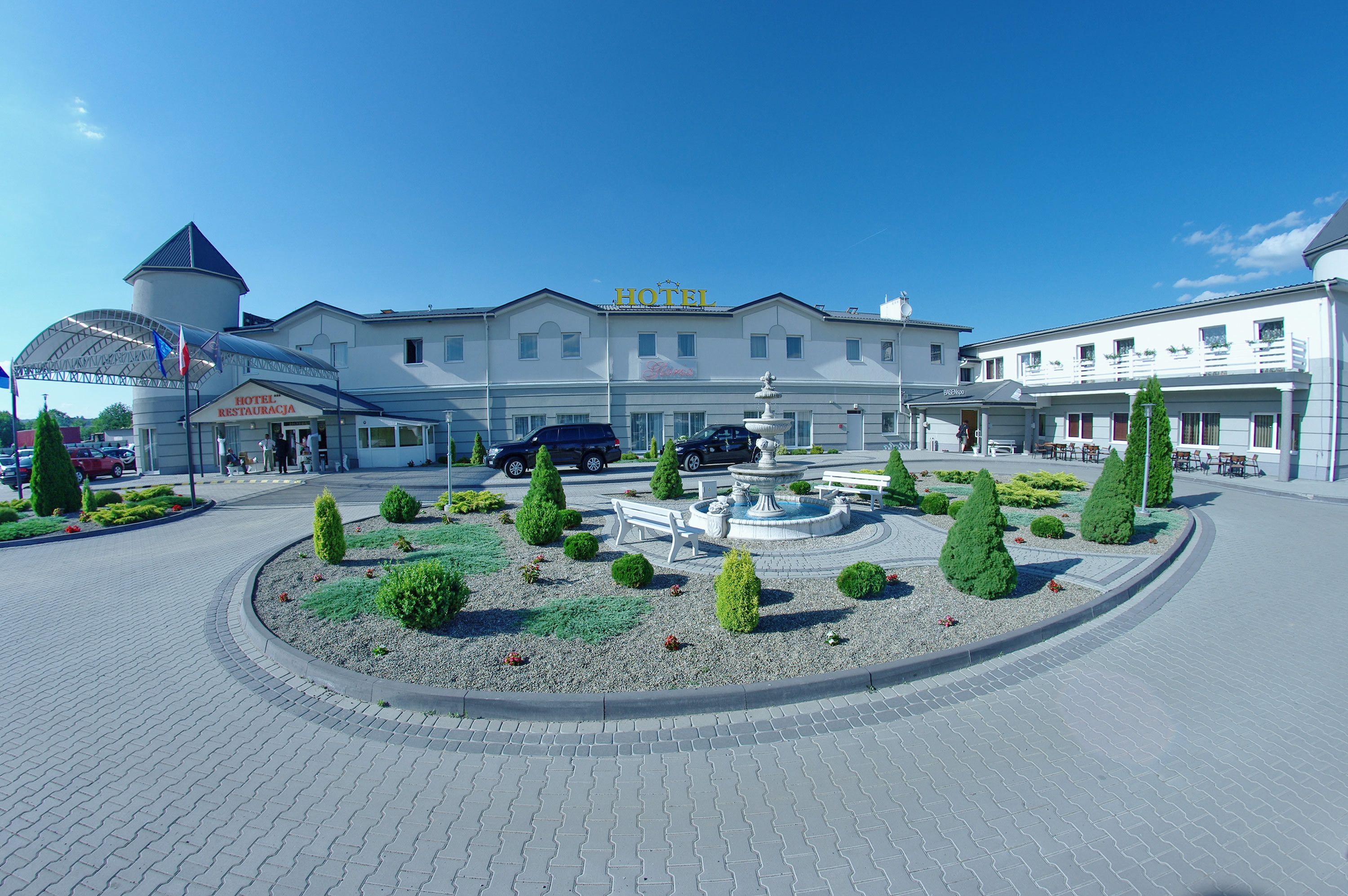 Een hotel met een centrale binnenplaats, een fontein en een vlaggenmast.