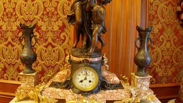 A clock with a statue of a woman and child on a marble table.