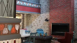 Un interior moderno con pared de ladrillo, chimenea y lámparas colgantes a rayas.