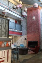 Un interior moderno con pared de ladrillo, chimenea y lámparas colgantes a rayas.