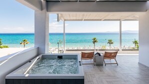 Un moderno espacio de spa con una bañera de hidromasaje, sillas de mimbre y vista a la playa y al océano.