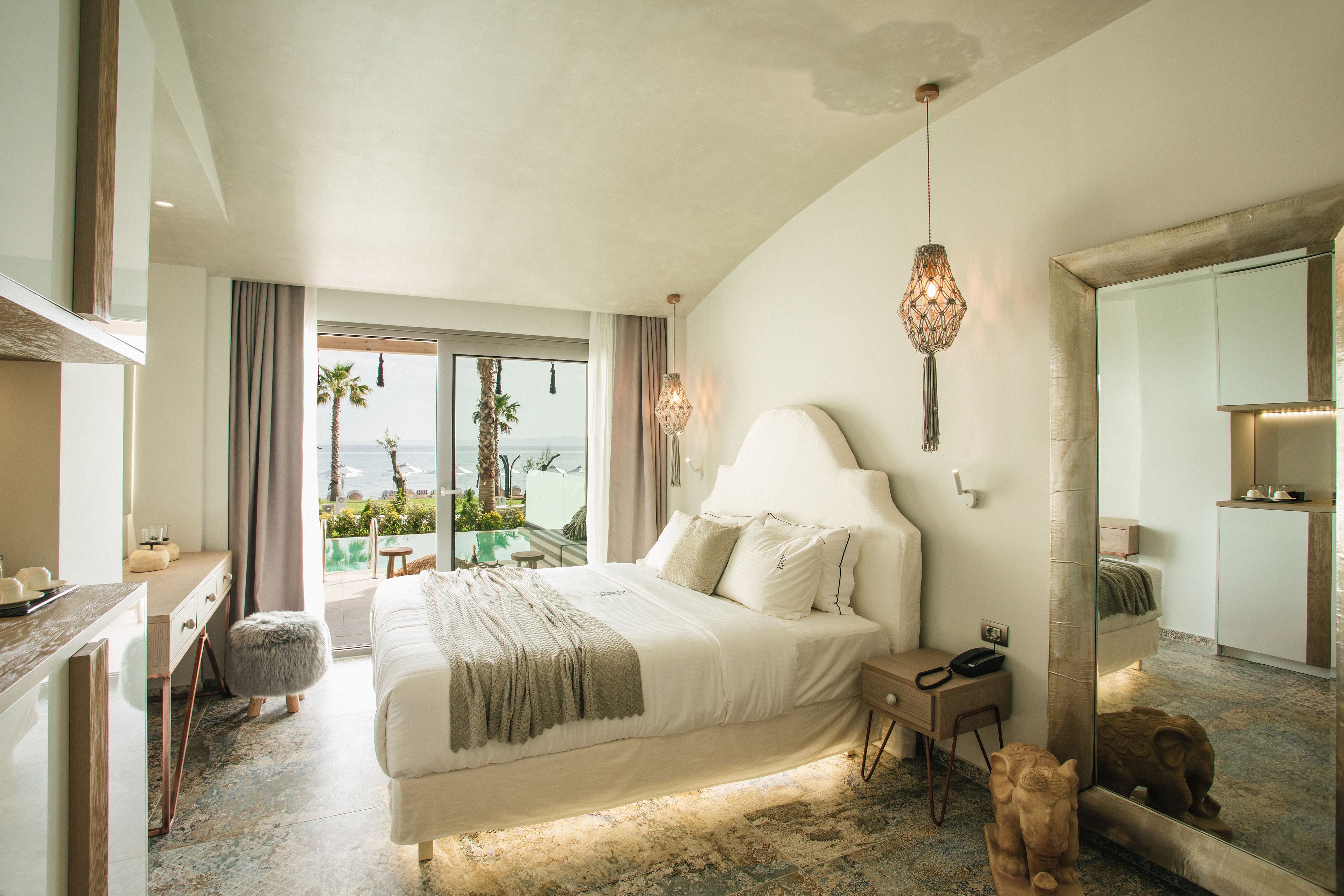 Ein Schlafzimmer mit Bett, Nachttisch, Lampe und einem großen Spiegel.