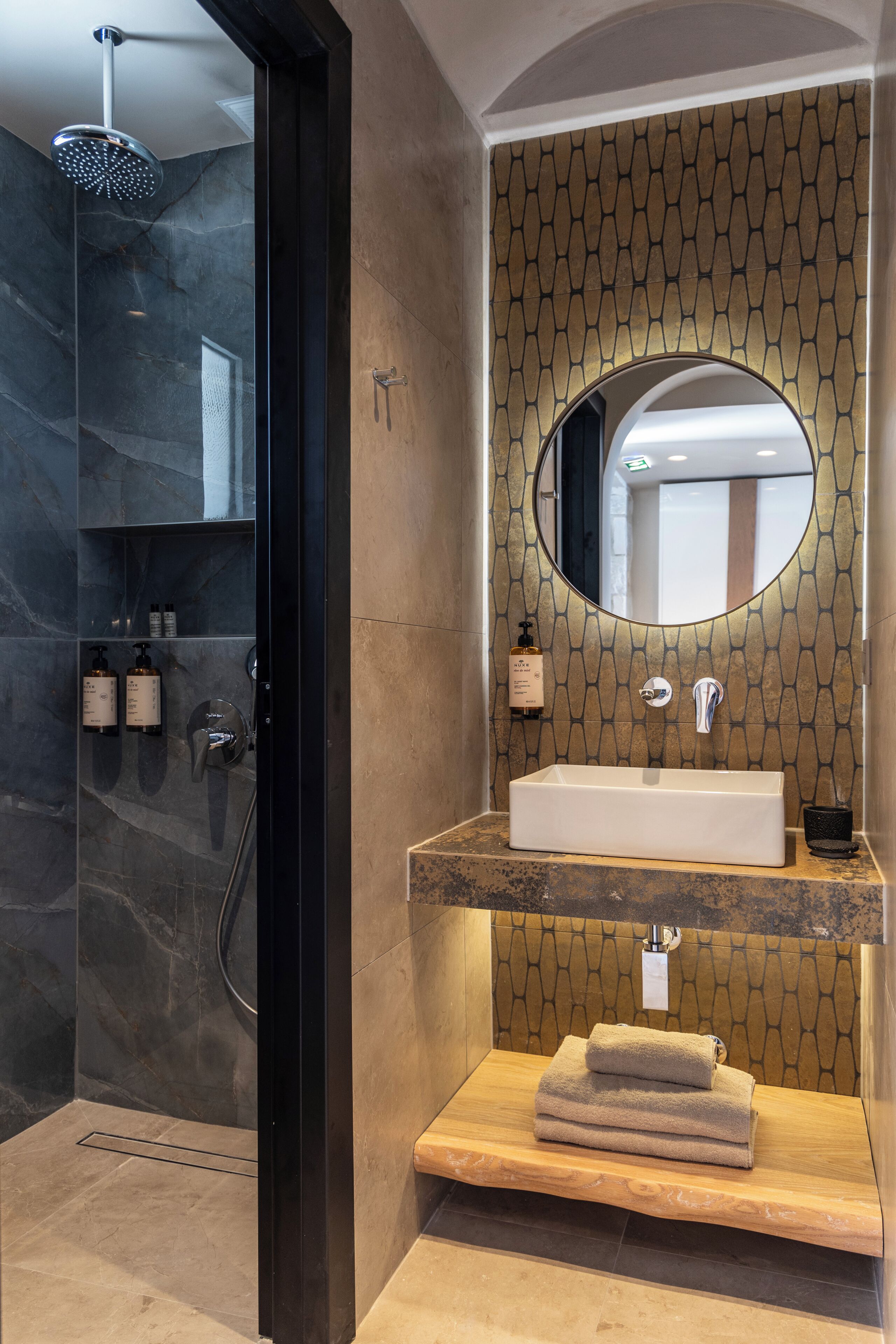 Un baño moderno con ducha, lavamanos y espejo.