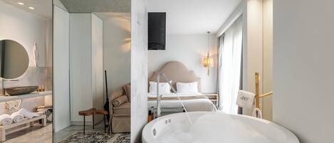 Un baño moderno con una bañera grande, un espejo redondo y un banco con toallas.