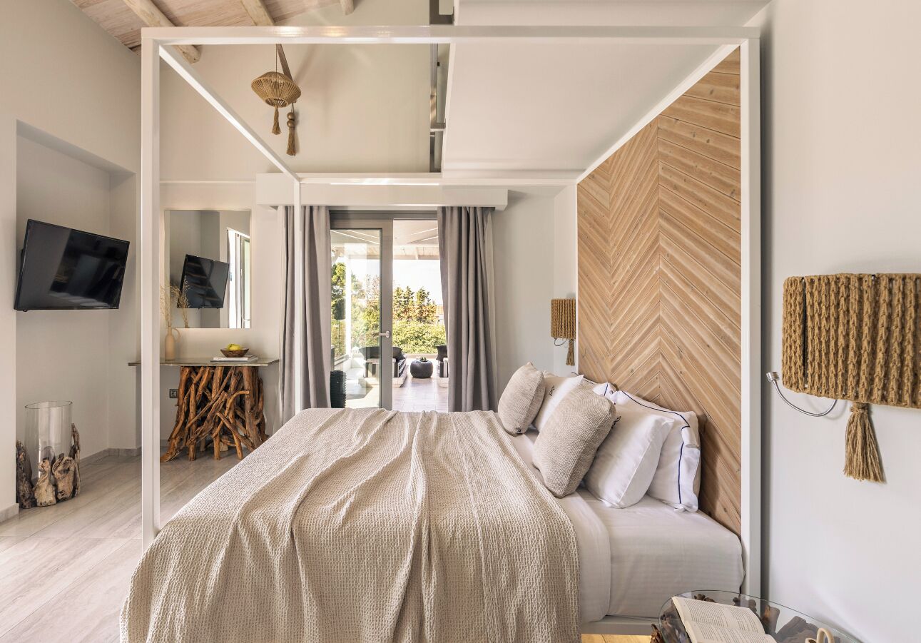 A modern bedroom with a large bed, a TV, and a view of the outdoors.