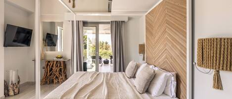 A modern bedroom with a large bed, a TV, and a view of the outdoors.