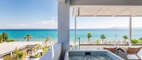 A modern hotel room with a large window overlooking a beach and the sea.
