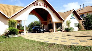 Un edificio con una amplia entrada en arco con la leyenda “CHALÈS” y un camino pavimentado que conduce a un automóvil estacionado.