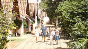 Un camino bordeado por edificios y vegetación, que sugiere un entorno de resort o hotel.