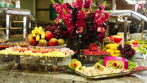 Un bufé con diferentes opciones de comida, incluyendo frutas, quesos y embutidos.