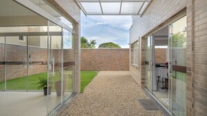 A modern building with glass doors, a gravel path, and a brick wall in the background.