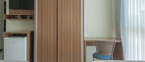 A hotel room with a wardrobe, a television, a desk, a chair, and a bed.