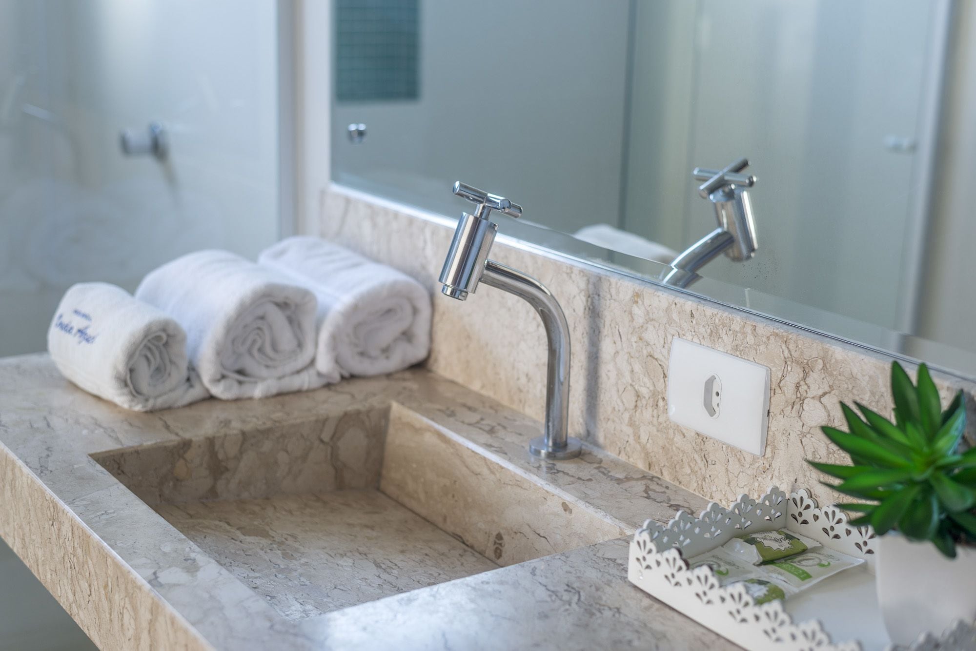 Une salle de bain avec un lavabo en marbre, un miroir et un porte-serviettes avec des serviettes pliées.