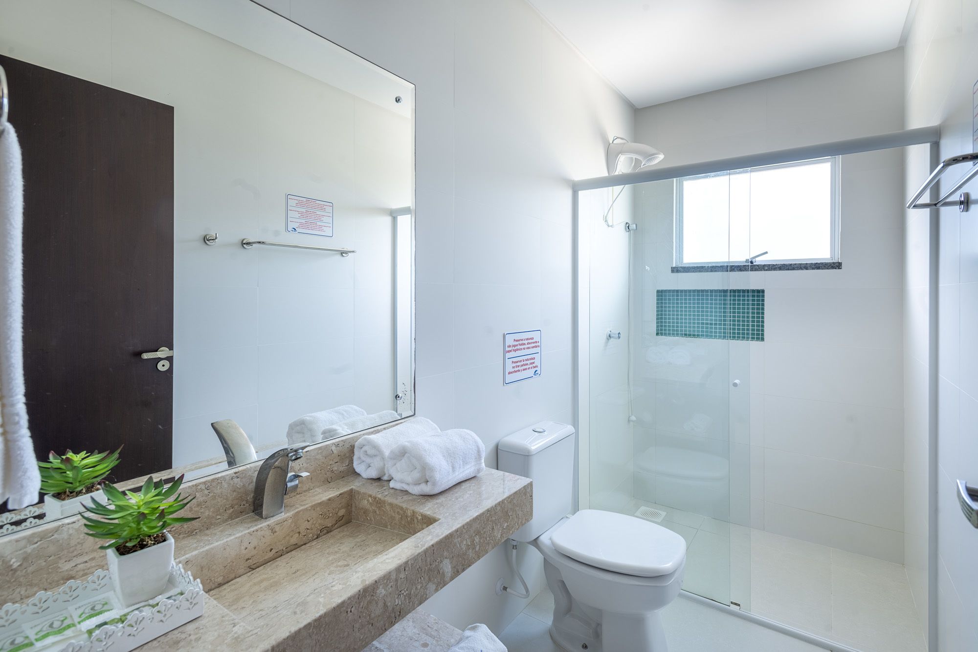 A modern bathroom with a glass shower enclosure, a sink with a marble countertop, and a toilet.
