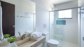 Un baño moderno con cabina de ducha de vidrio, un lavabo con encimera de mármol y un inodoro.