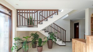 A staircase with wooden railings and multiple potted plants at the base.