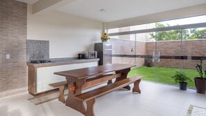A modern kitchen with a granite countertop, stainless steel appliances, and a wooden dining table with benches.