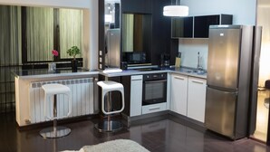 Una cocina moderna con una isla central, electrodomésticos de acero inoxidable y una lámpara colgante.