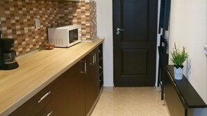 A kitchen with a microwave, cabinets, and a tiled backsplash. - Sudului 810 by MRG Apartments (Bucharest)