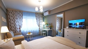 A hotel room with a large bed, a desk, a chair, a small table, a mirror, and a television. - Sudului 810 by MRG Apartments (Bucharest)