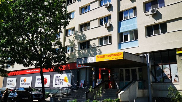 A multi-story building with air conditioning units, a storefront with signage, and a tree in the foreground. - Sudului 810 by MRG Apartments (Bucharest)