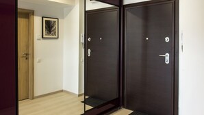 Un pasillo con una puerta de madera, una puerta de madera oscura y un cuadro en la pared.