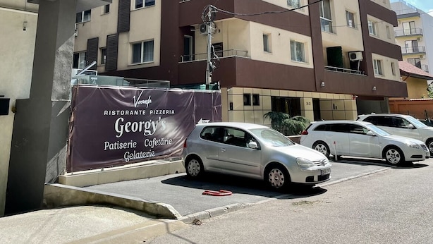 Un edificio residencial de varios pisos con balcones y un cartel que anuncia una pizzería.