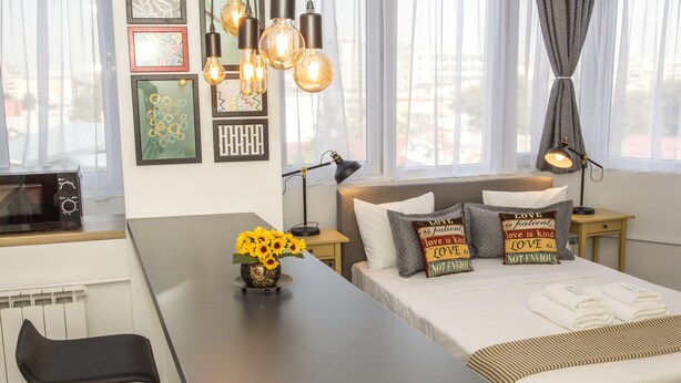 A modern hotel room with a bed, bedside tables, a desk, and a chair. - Studio L by MRG Apartments (Bucharest)
