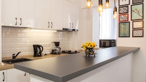 A modern kitchen with white cabinets, a large island, and a coffee maker. - Studio L by MRG Apartments (Bucharest)