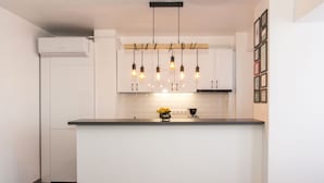 A modern kitchen with white cabinets, a central island, and a hanging light fixture. - Studio L by MRG Apartments (Bucharest)