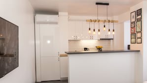 A modern kitchen with white cabinetry, a central island, and pendant lighting. - Studio L by MRG Apartments (Bucharest)