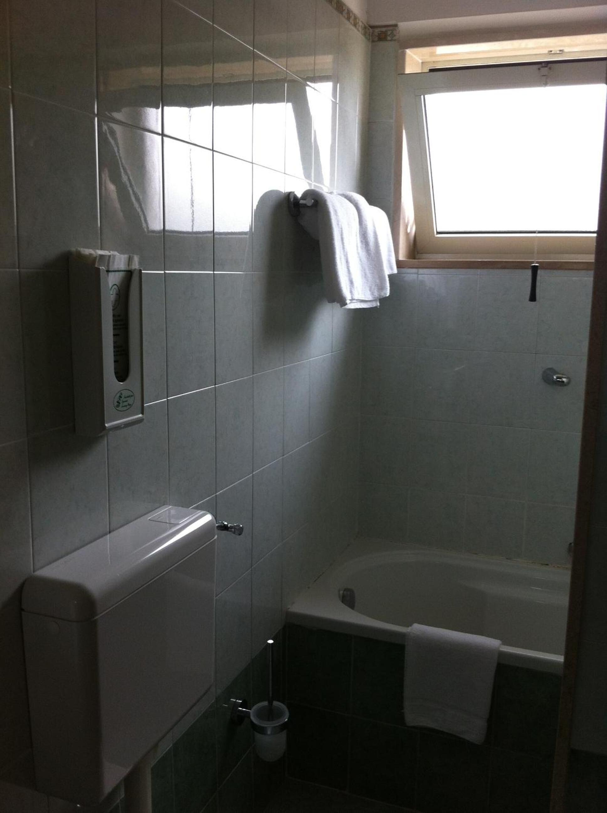 Un baño con bañera, toallero y secador de manos.