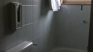 Un baño con bañera, toallero y secador de manos.