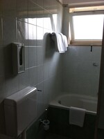 Un baño con bañera, toallero y secador de manos.