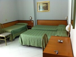 A hotel room with two single beds, a wooden desk, a chair, and a small table.