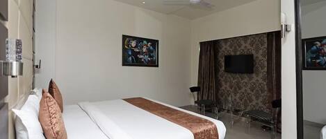 A hotel room with a bed, a ceiling fan, a TV, and a bathroom visible through an open door.