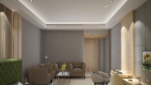 A modern living room with a sofa, armchairs, a coffee table, and a small side table with decorative items. - Hotel D Grand (Bareilly)