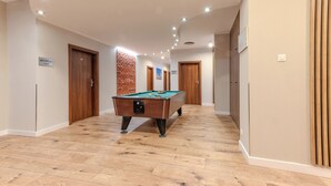 A hallway with a pool table, wooden doors, and a reception area. - Hotel Topaz Poznań Centrum (Poznan)